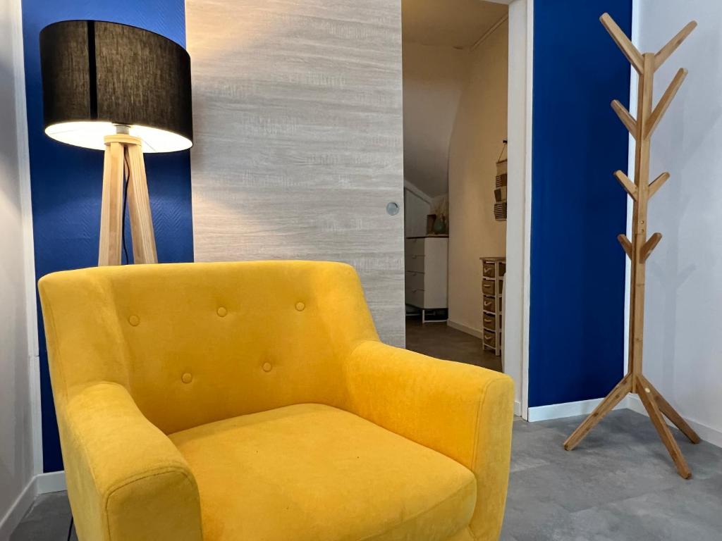 een gele stoel in een woonkamer met een lamp bij L'Hypercentral in Cauterets