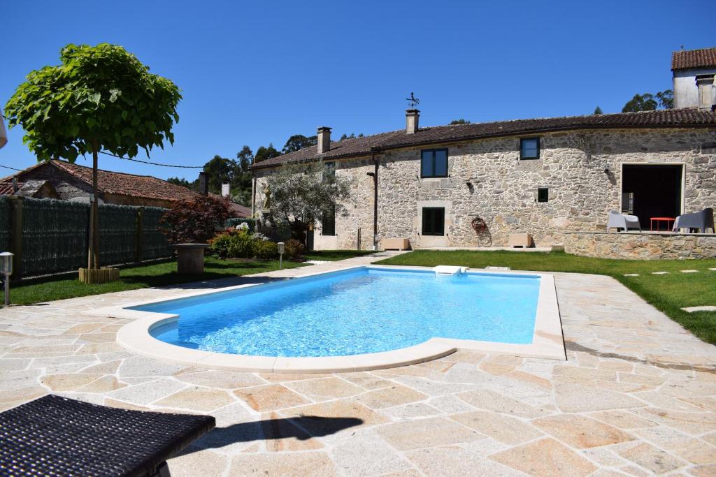 una piscina di fronte a una casa in pietra di A Casa Romeu a Santiago de Compostela