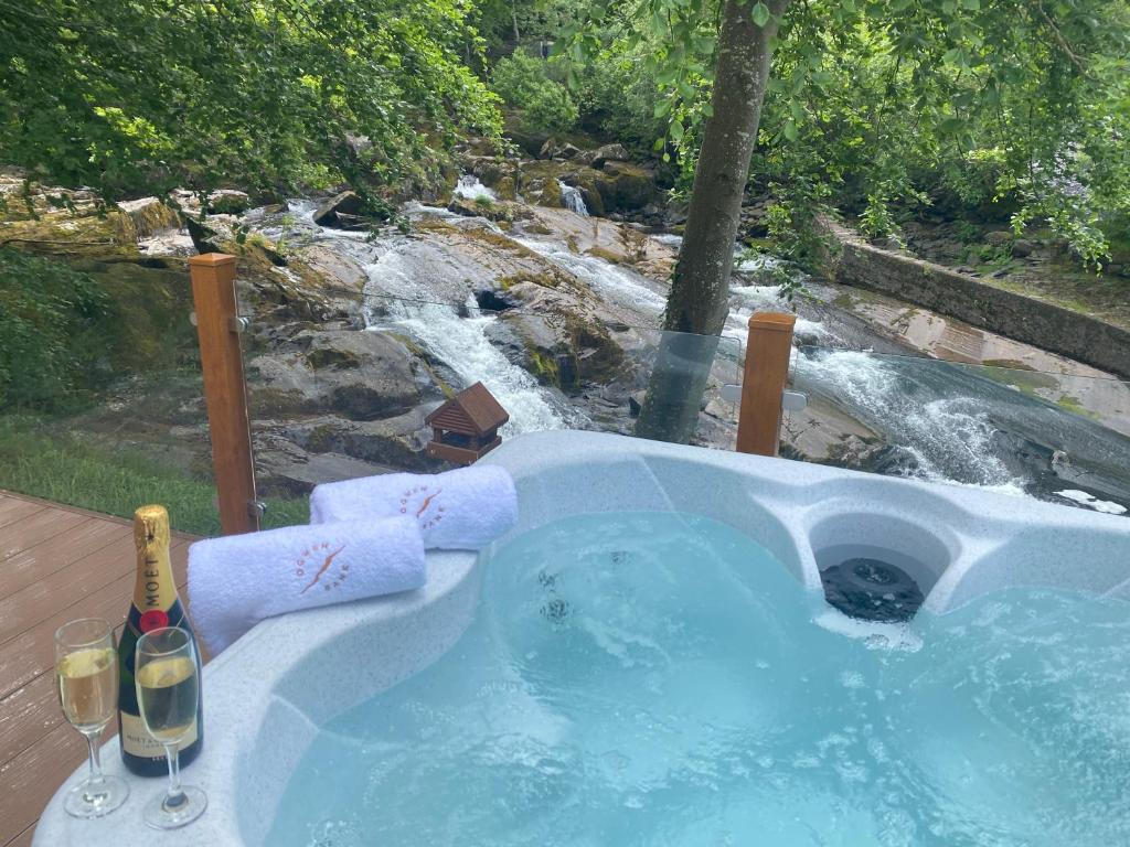 a hot tub with two glasses of wine in front of a waterfall at V13 - The Falls with Hot Tub in Bethesda