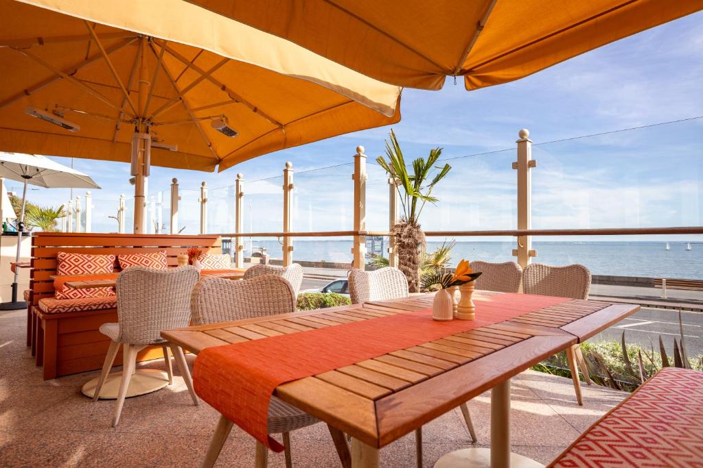 a wooden table with chairs and an umbrella at Roslin Beach Hotel in Southend-on-Sea