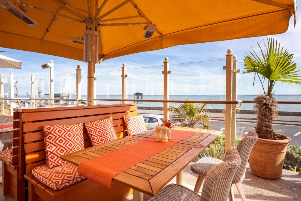 a table and chairs on a patio with an umbrella at Roslin Beach Hotel in Southend-on-Sea