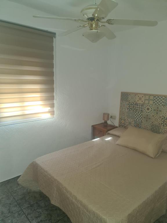 Schlafzimmer mit einem Bett, einem Deckenventilator und einem Fenster in der Unterkunft Apartamento Mari in Agua Amarga