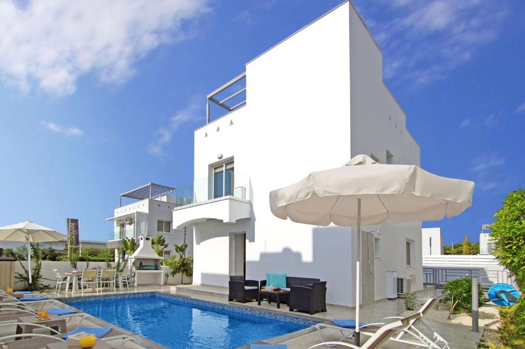 une villa avec une piscine et un parasol dans l'établissement Villa Atlantia, à Ayia Napa