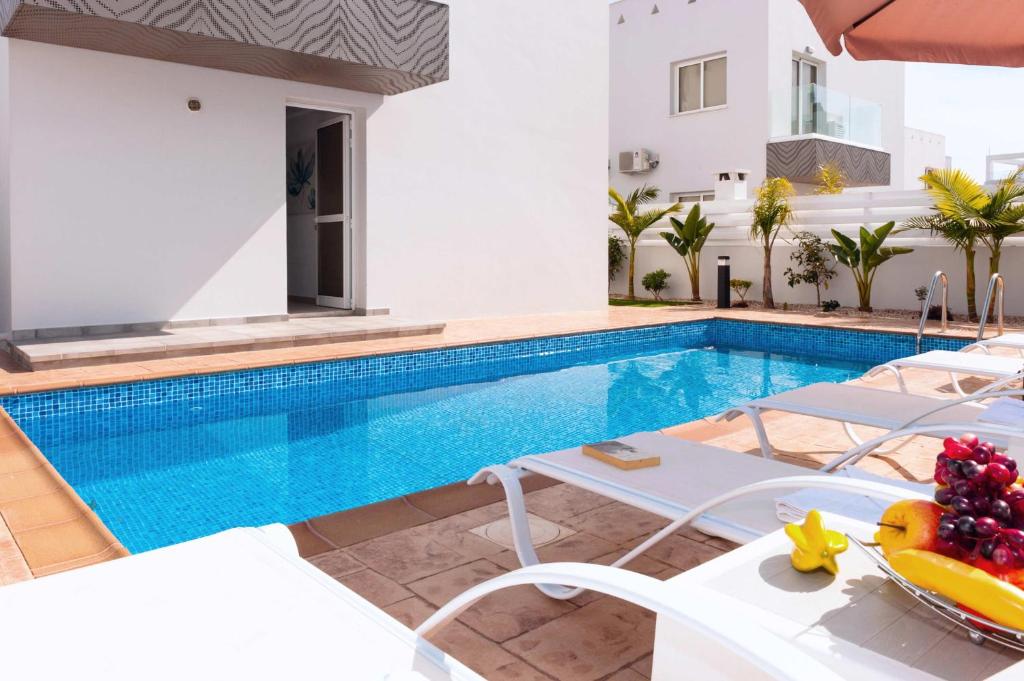 a swimming pool with white chairs and a villa at Villa Diamanta in Ayia Napa