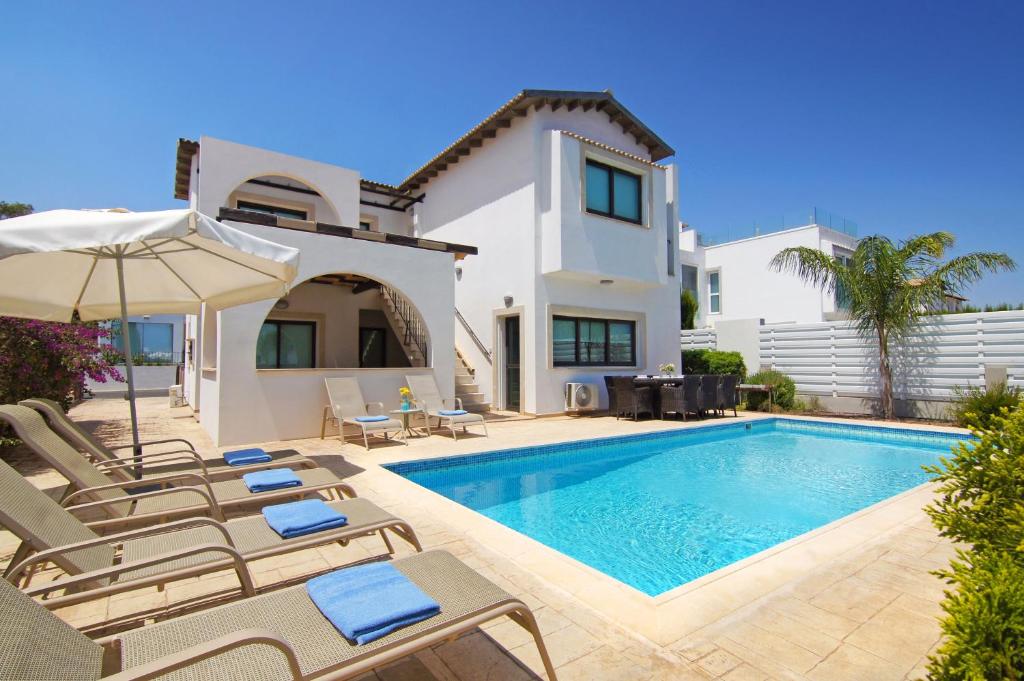 a villa with a swimming pool in front of a house at Villa Greko in Protaras