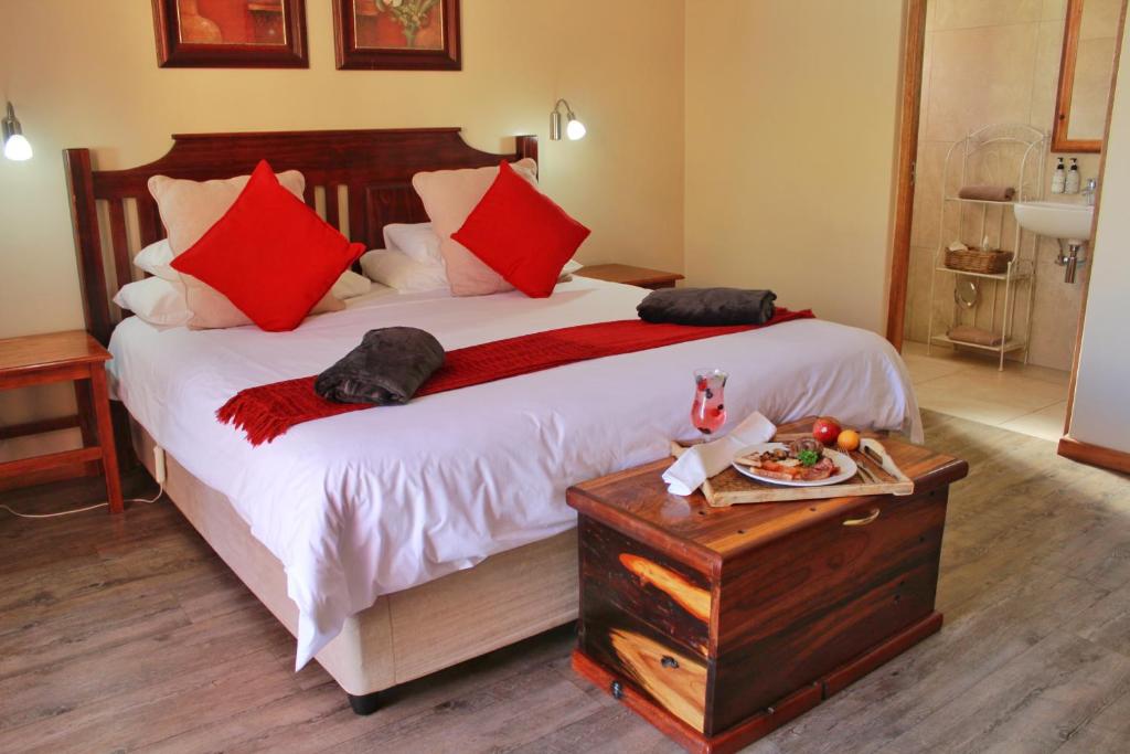 a bedroom with a large bed with red pillows at 17 on Bird Guest House in Beaufort West