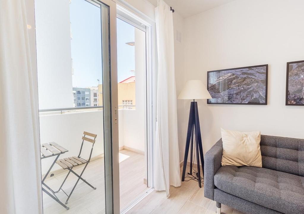 ein Wohnzimmer mit einem Sofa und einem Stuhl in der Unterkunft Moderno apartamento urbano en barrio histórico 2ºI in Santa Cruz de Tenerife