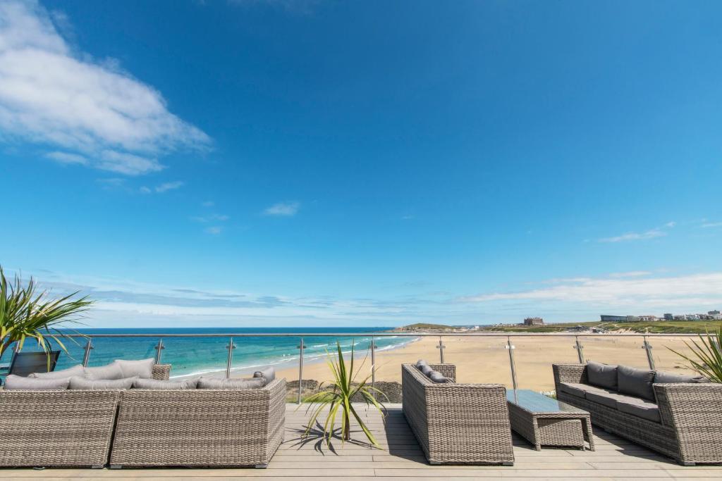 a row of wicker chairs on a beach with the ocean at Fistral Beach Hotel and Spa - Adults Only in Newquay
