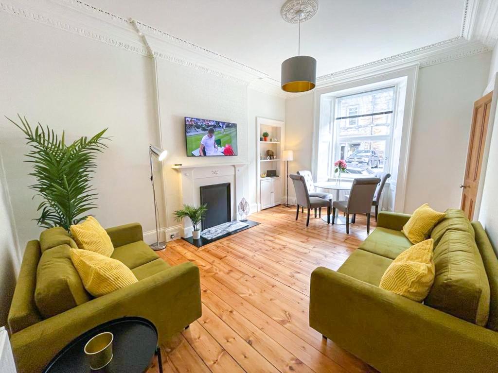 ein Wohnzimmer mit 2 grünen Sofas und einem Tisch in der Unterkunft Desirable 2 Bed Apt Near Edinburgh Castle in Edinburgh