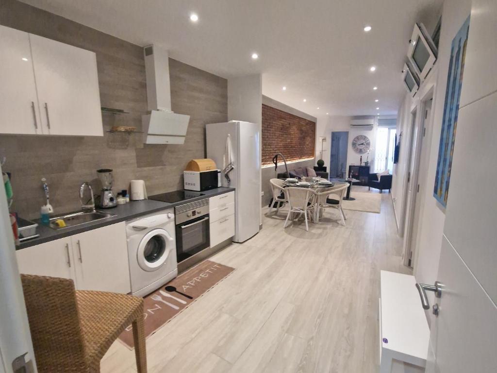 een keuken en een woonkamer met een tafel en een koelkast bij Barcelona Apartamento en planta baja con Terraza in Hospitalet de Llobregat