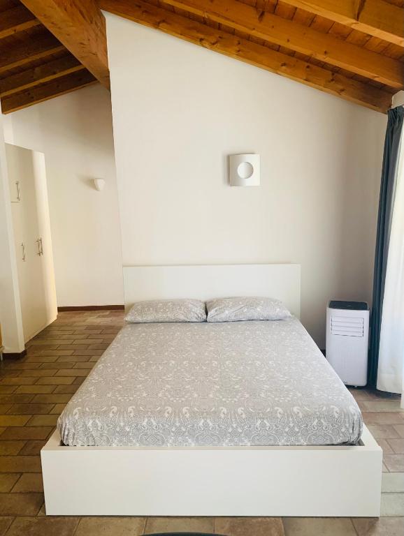 białe łóżko w sypialni z drewnianym sufitem w obiekcie Casa Cleopatra w Bergamo