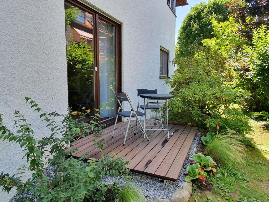 una terraza de madera con 2 sillas y una mesa. en Ferienwohnung Stadler en Langenargen