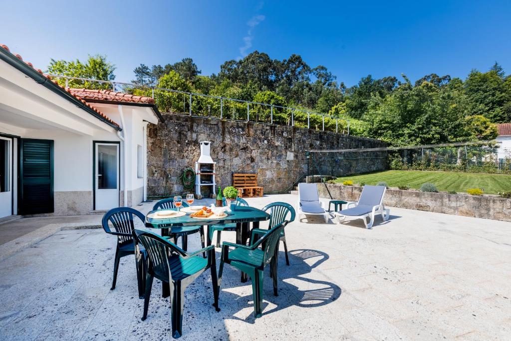 a patio with a table and chairs and a stone wall at Casa da Leira in Vila Nova de Cerveira
