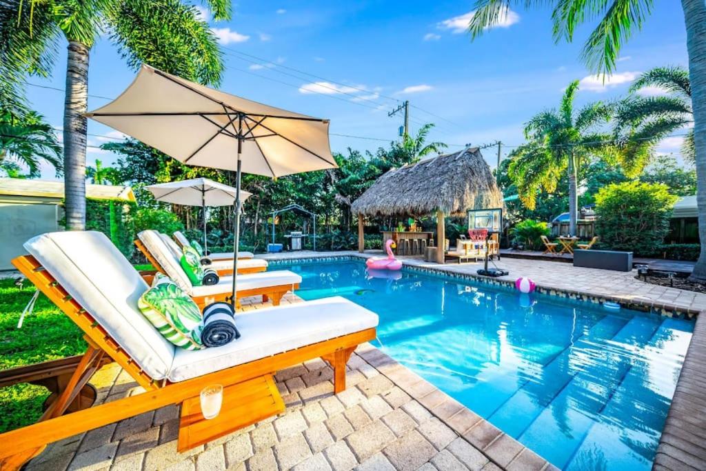 a pool with two lounge chairs and an umbrella at Chique Pool and Tiki Resort in Pompano Beach