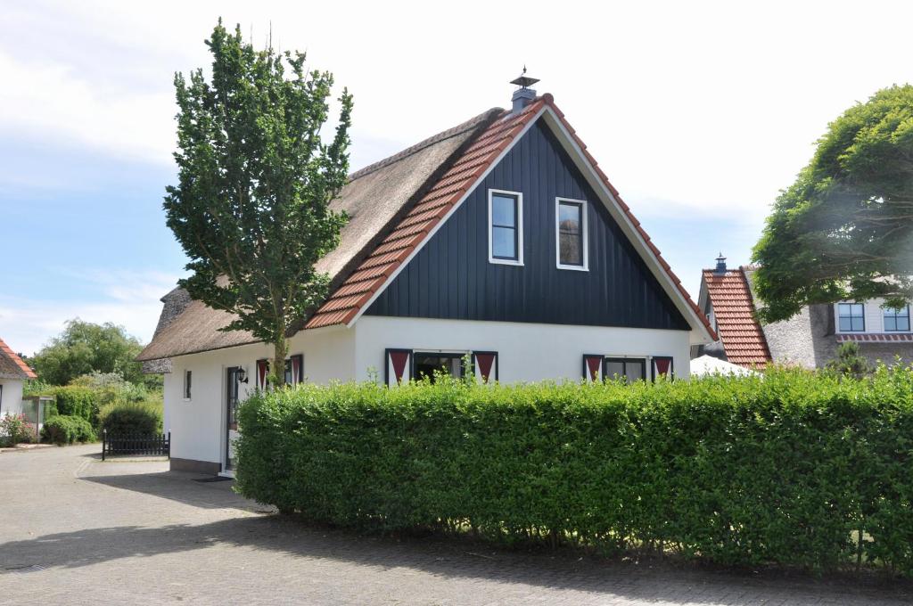 una casa en blanco y negro con un árbol delante en Buitenplaats 86, en Callantsoog