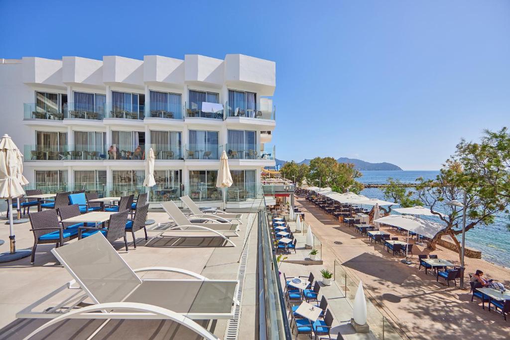 a hotel with chairs and umbrellas on a beach at Hotel Ilusion Moreyo - Adults Only in Cala Bona