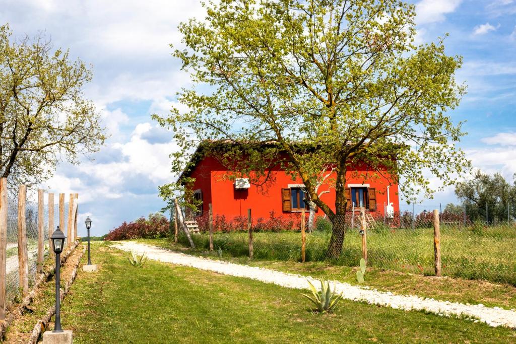 czerwony dom z drzewem obok drogi w obiekcie Agriturismo Poggio Degli Ulivi w mieście Bomarzo