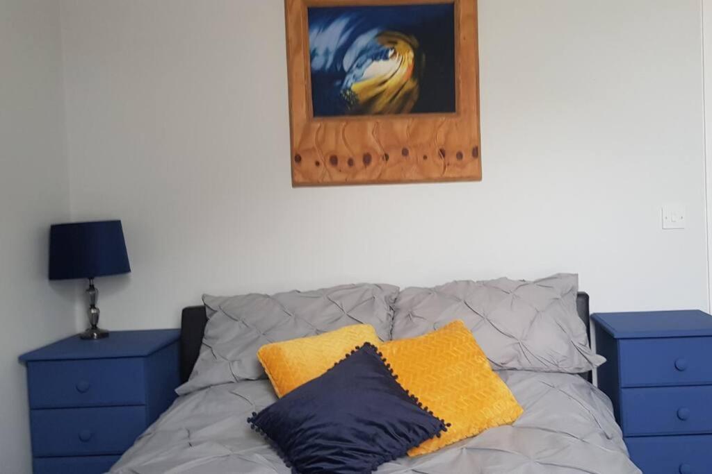 a bed with two pillows and a picture on the wall at Sea Reach Apartment, 2 minutes from beach and town in Newquay