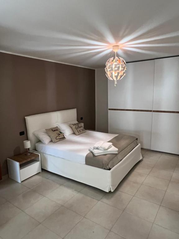 1 dormitorio con cama blanca y lámpara de araña en Nial House, en Monopoli