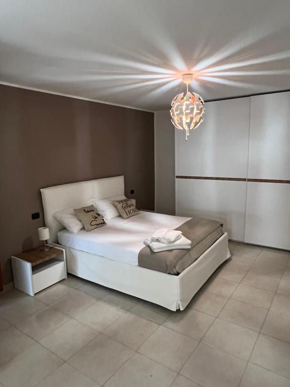a bedroom with a white bed and a chandelier at Nial House in Monopoli