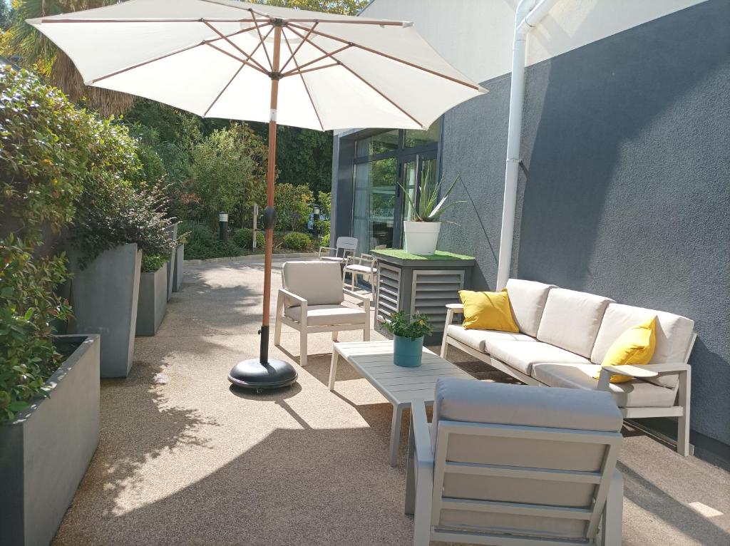 a patio with a couch and an umbrella and chairs at Le Cannet Appart'S in Le Cannet