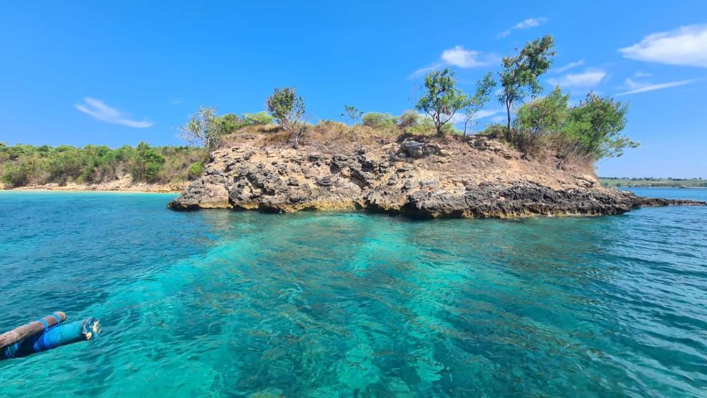 una persona tumbada en el agua cerca de una isla en Panorama Ekas, en Ekas
