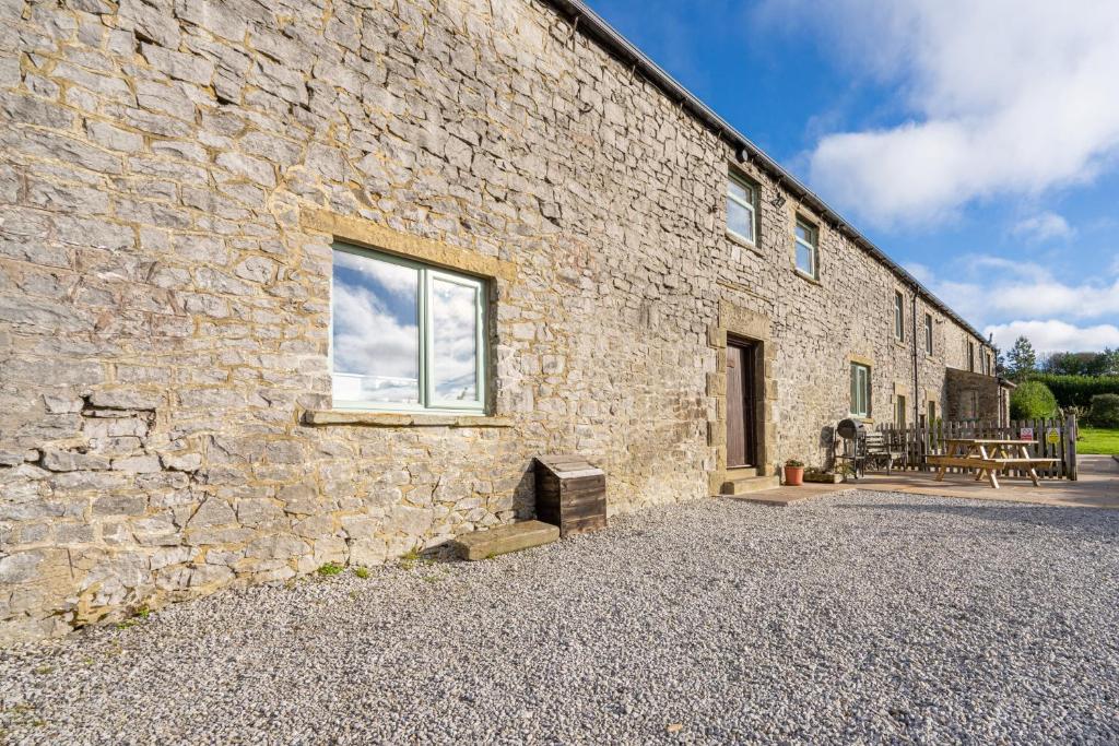 a stone building with a window and a patio at The Holmes Barn - Sleeps 16 - Peak district in Buxton