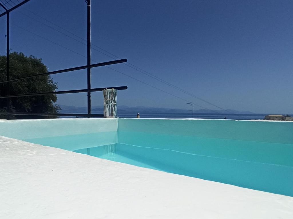 a blue swimming pool with a view of the ocean at Seaview Mini Villa with Private Pool - 200 metres from the beach in Perama