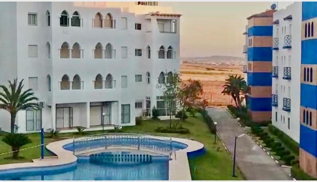 a large white building with a swimming pool in front of it at TANGER/ASILAH: APPART 50m2 FACE MER ET PISCINES, 5 PLACES, TOUT ÉQUIPÉ+WIFI+CLIM in Briech