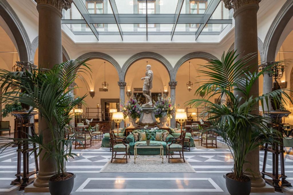 a lobby with a fountain and chairs and a statue at Palazzo Portinari Salviati Residenza D'Epoca in Florence