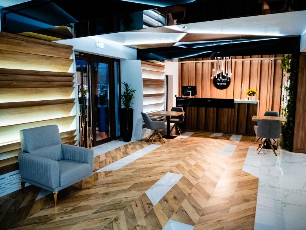 a lobby with a blue chair and wooden floors at Hotel Goya Boutique in Târgu Jiu