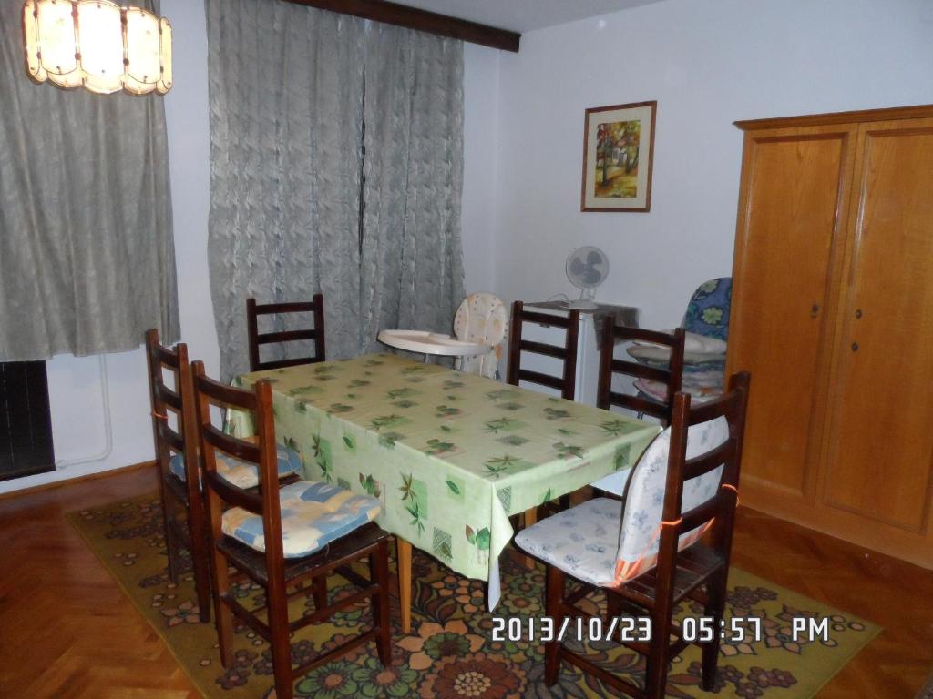 a dining room with a green table and chairs at Hársfaapartman és vendégház in Gyula