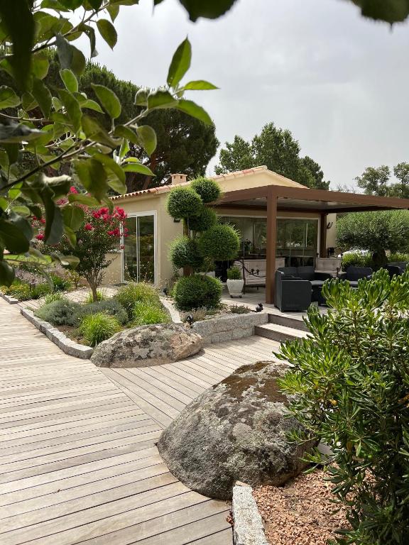 un jardin avec une terrasse en bois et une maison dans l'établissement Les Jardins De Santa Giulia - Charmante chambre dhte 1, à Porto-Vecchio