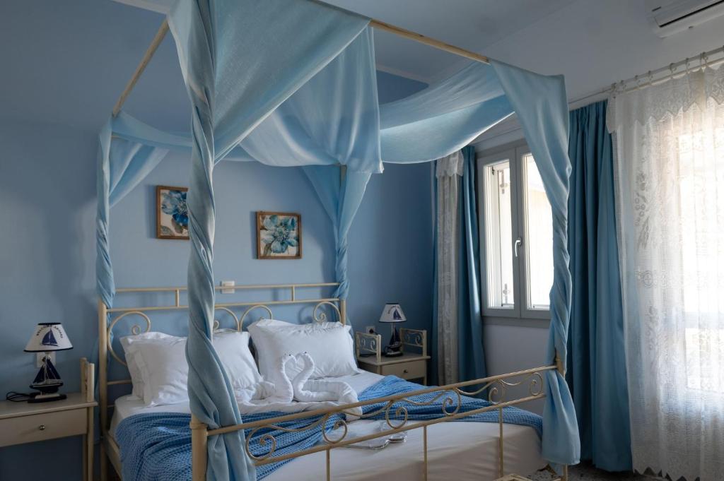 a bedroom with a canopy bed with blue walls at Giasemi Room No 5 Astypalea in Livadi Astypalaias