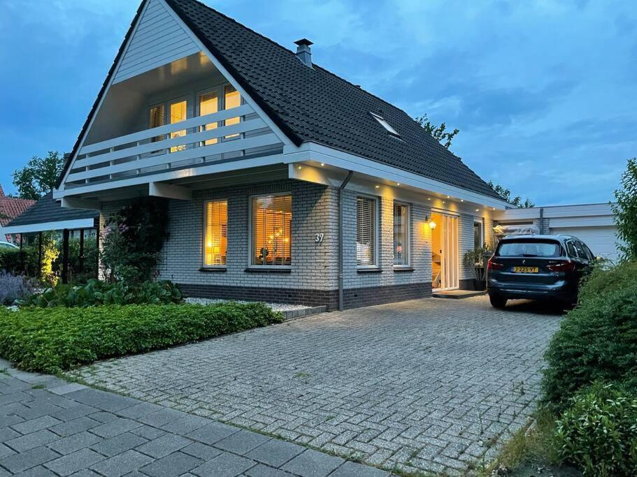 een huis met een auto ervoor geparkeerd bij Luxury villa with private Sauna and Jacuzzi in Holland in Drachten