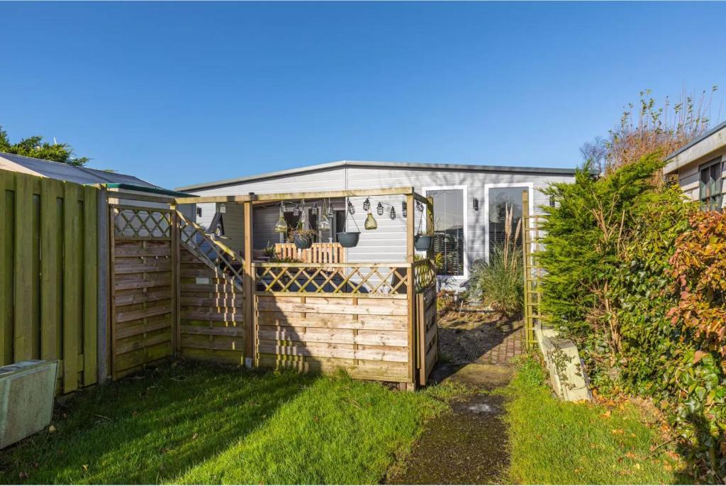 a greenhouse in a garden next to a fence at Oase aan de Kaag in Warmond