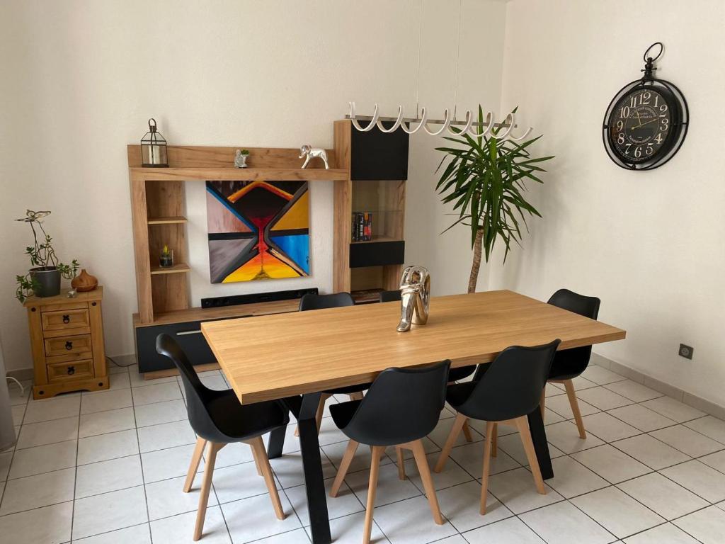 een eetkamer met een houten tafel en stoelen bij APPARTEMENT SPACIEUX in Orange