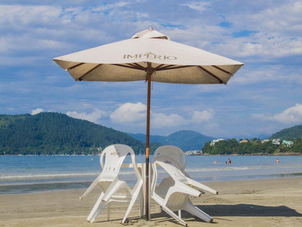two chairs and an umbrella on the beach at Pousada Maanaim in Ubatuba