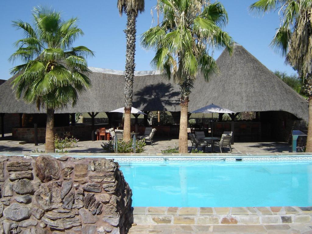 a resort with a swimming pool with palm trees at Rooisand Desert Ranch in Chausib