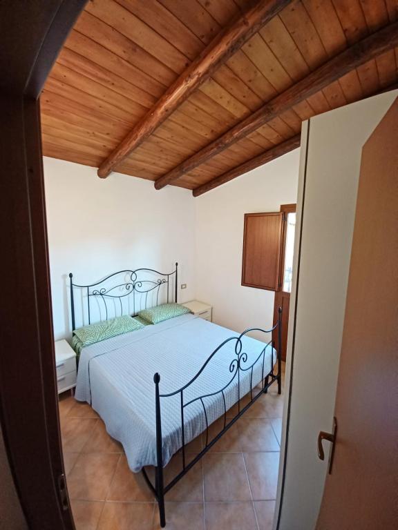 1 dormitorio con cama y techo de madera en Casa Dalena, en Lu Razzoni