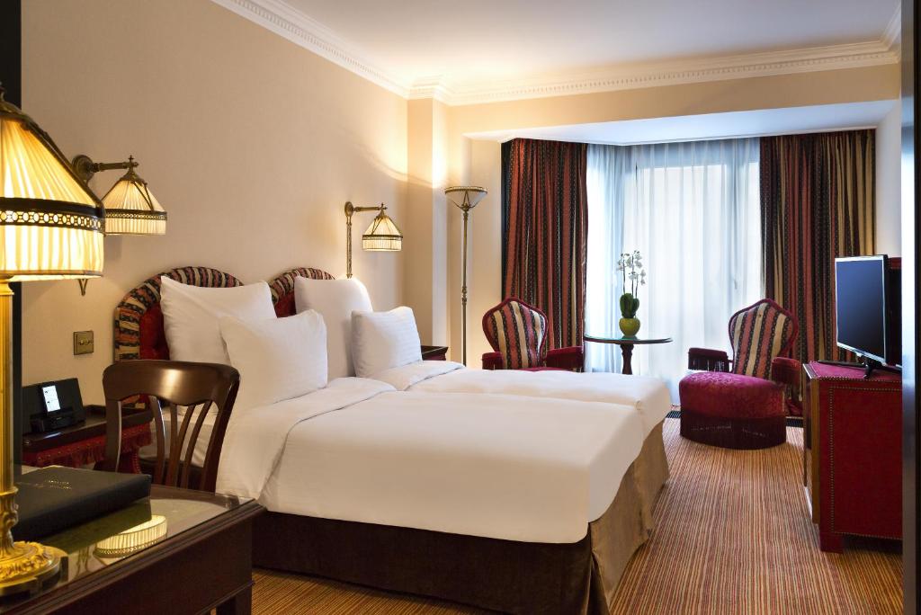 a hotel room with a large white bed and a desk at Hotel Barsey by Warwick in Brussels