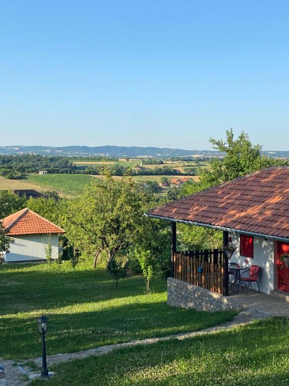 una casa con un porche y un patio con un campo en Bas u inat babarogama, en Koraćica