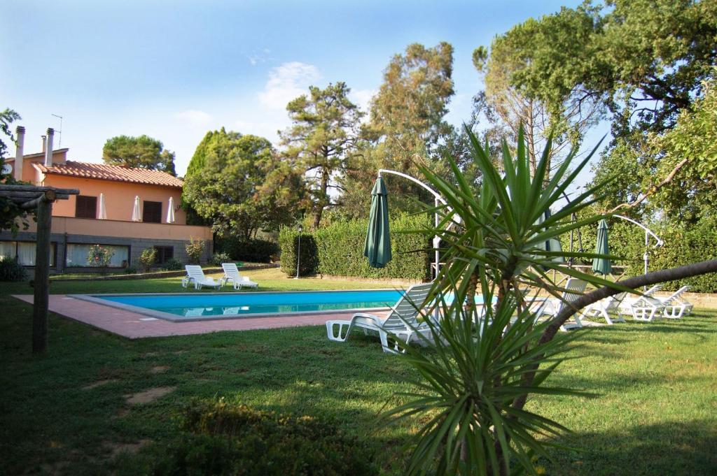 um quintal com uma piscina com cadeiras e um guarda-sol em Casa Grion em Corchiano