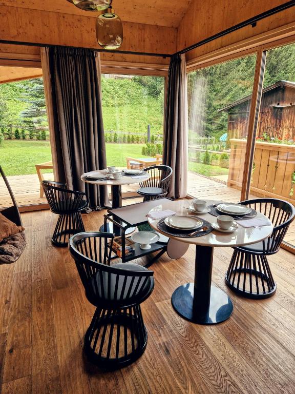una sala da pranzo con tavoli, sedie e una grande finestra di Chalet La Ciaseta a Pozza di Fassa