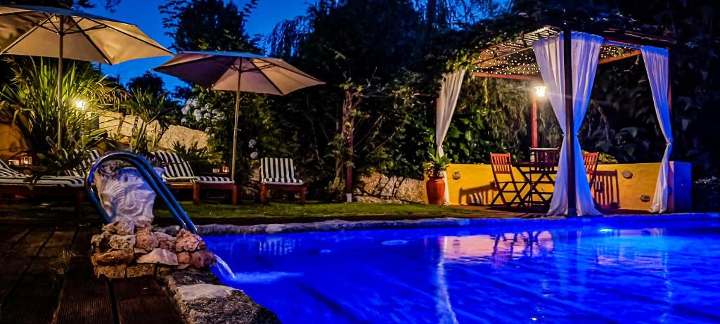 a swimming pool at night with umbrellas and a pool at Casa da Benfeitoria in Guimarães