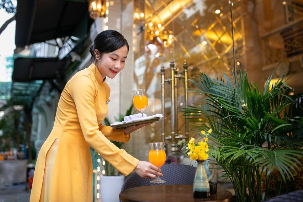 una mujer con un vestido amarillo sosteniendo un plato de comida en Hanoi Diamond King Hotel & Travel en Hanói