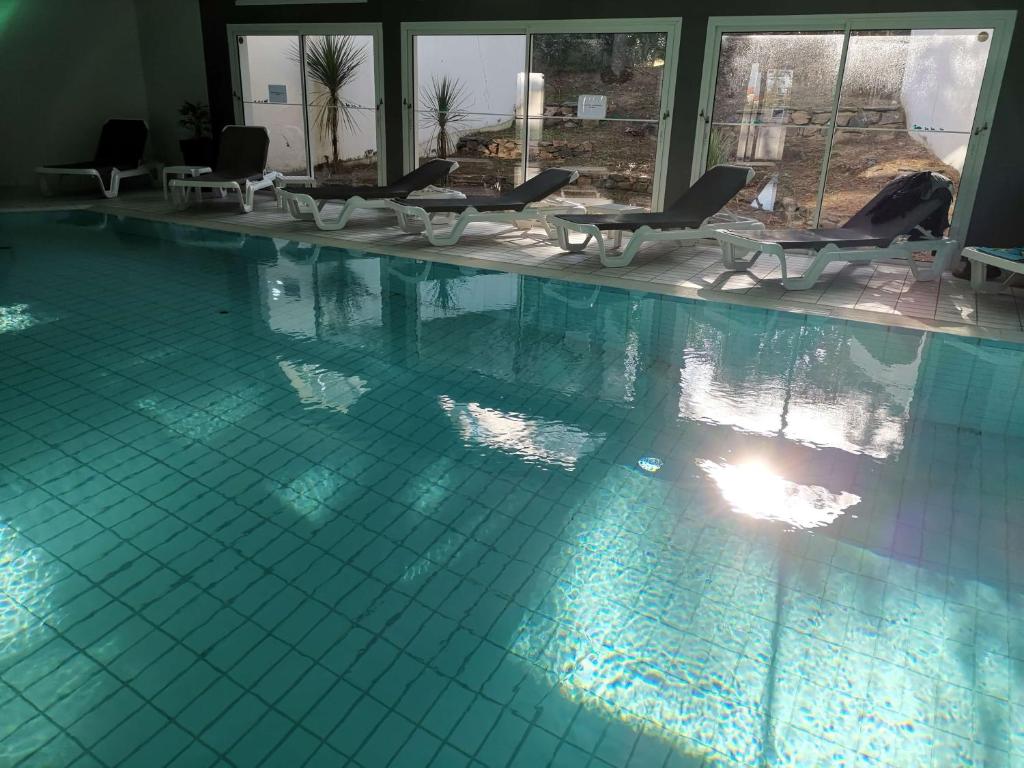 a large swimming pool with chairs in a building at Logis Les Cols Verts in La Tranche-sur-Mer