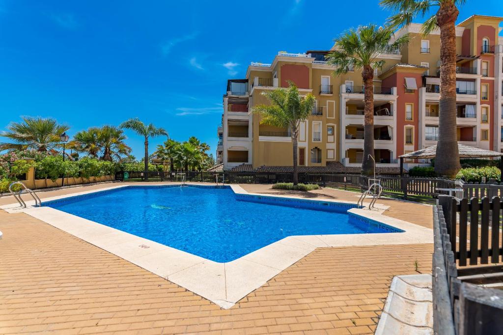 a swimming pool in front of a building with palm trees at Playa Grande by Ĥ in Isla del Moral