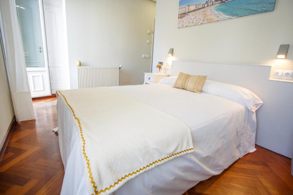 Un dormitorio con una gran cama blanca con puntadas amarillas en Hostal Costa Coruña, en A Coruña