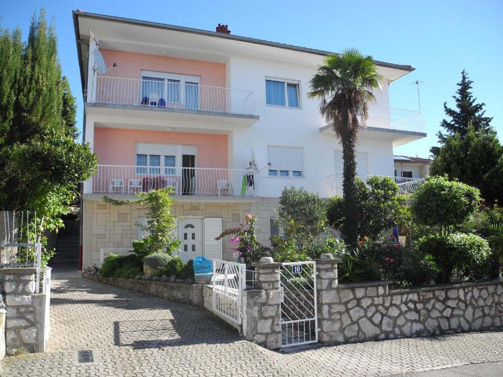 a white house with a palm tree in front of it at Apartments Pavelić in Crikvenica